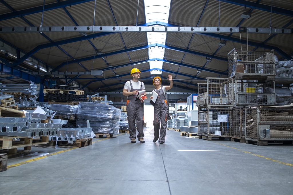 Factory workers walking through large production hall.